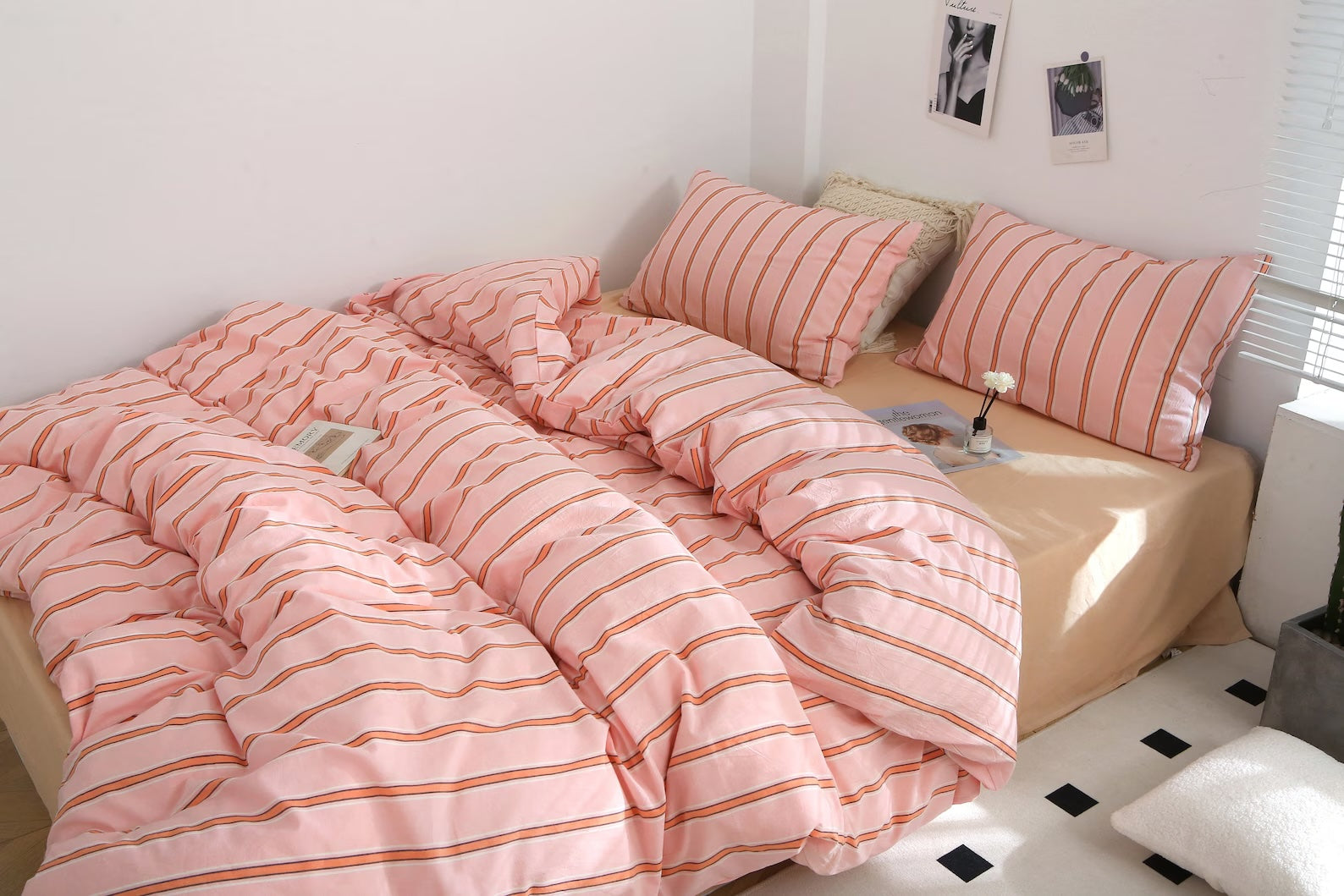 Bed with pink striped bedding and pillows in a room with a window and light fixture.