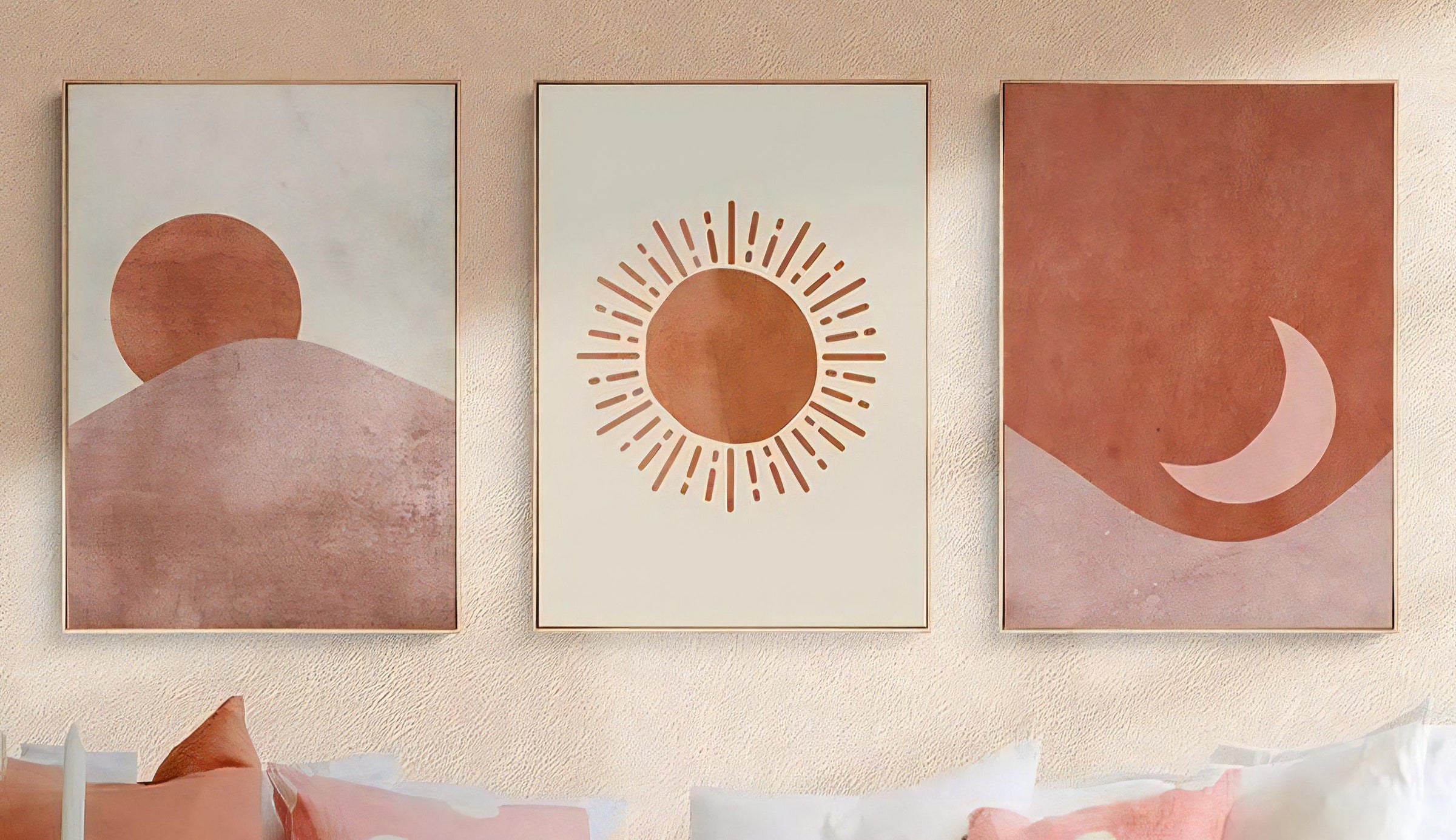 Three abstract wall art pieces on a beige wall above a white sofa with colorful cushions.