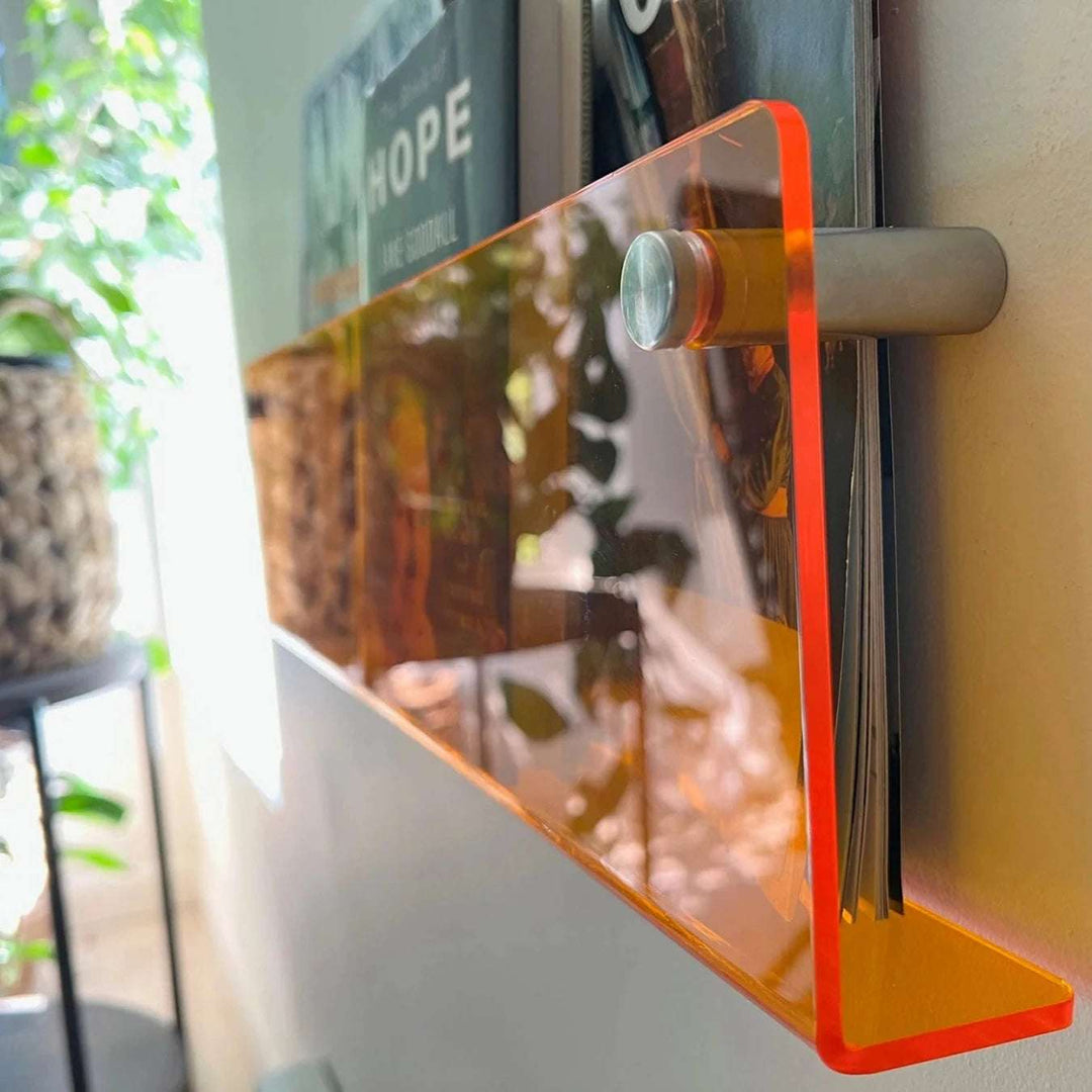 VibeCore Acrylic Wall Mounted Floating Magazine Shelf in orange, side view close-up showcasing its smooth surface and contemporary design, perfect for stylish magazine storage.