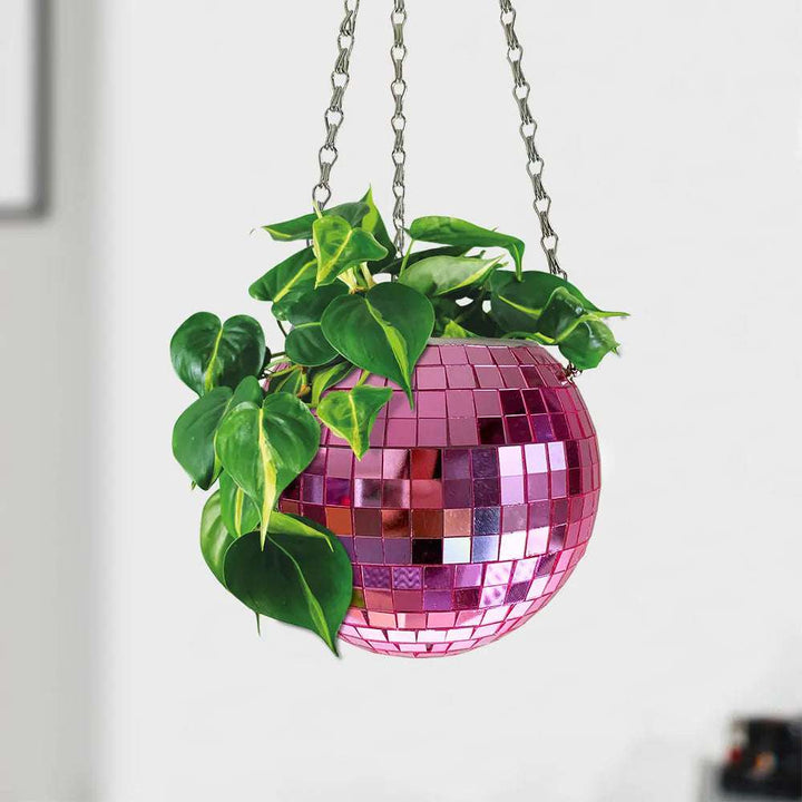 VibeCore Disco Ball Planter in pink, hanging with a shiny, reflective mirror-ball surface. This retro-inspired planter adds a pop of color and a playful vibe to any space. Perfect for showcasing plants, the disco ball design brings a fun, vibrant touch to your living room, bedroom, or office decor.