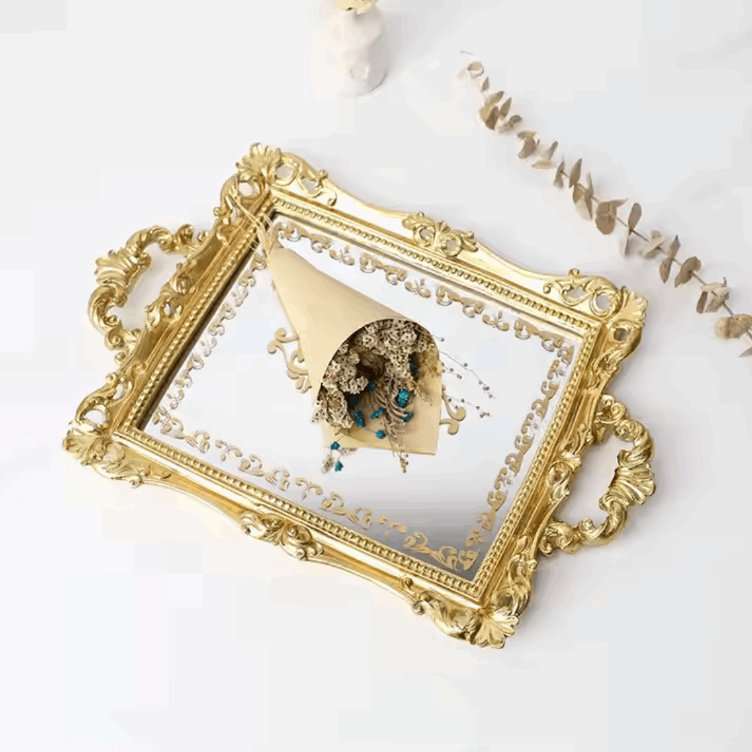 Angled aerial view of a luxurious gold mirror tray with intricate gold detailing and a flower bouquet resting on it. Reflective surface and elegant design, perfect for coquette aesthetic decor.