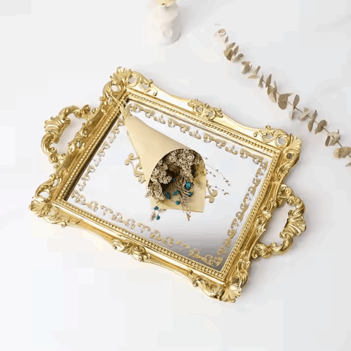 Angled aerial view of a luxurious gold mirror tray with intricate gold detailing and a flower bouquet resting on it. Reflective surface and elegant design, perfect for coquette aesthetic decor.