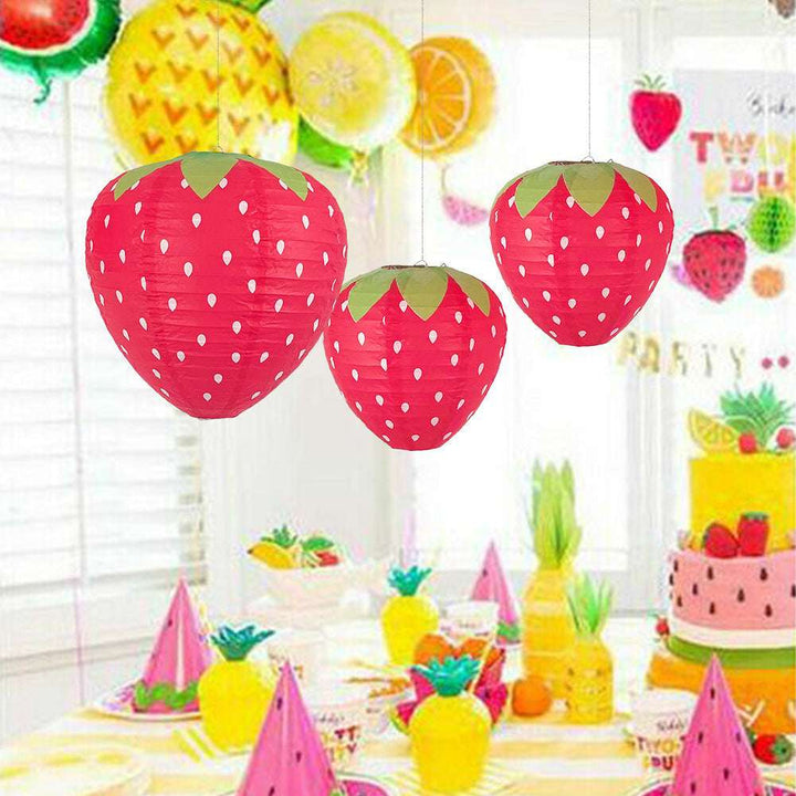 VibeCore Strawberry Paper Lantern Pendant hanging above a table, casting a soft, colorful light, enhancing the playful and whimsical vibe of the room with its charming strawberry design.