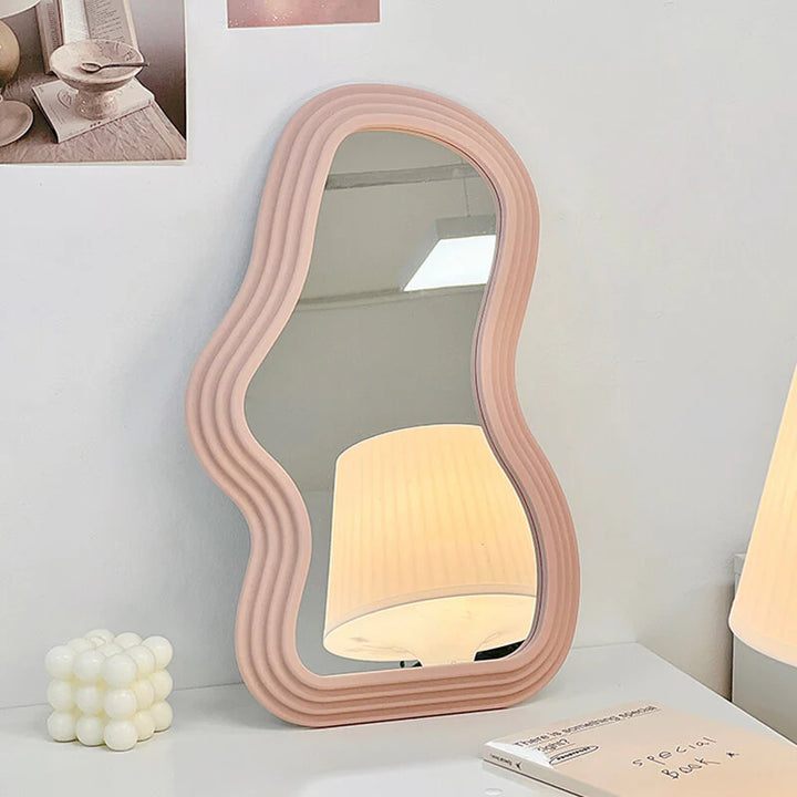 VibeCore Abstract Curve Wall Mirror Light Pink Curve Against Wall: A light pink curved abstract wall mirror leaning against a wall, offering a contemporary and stylish touch with its unique design and smooth, flowing lines.