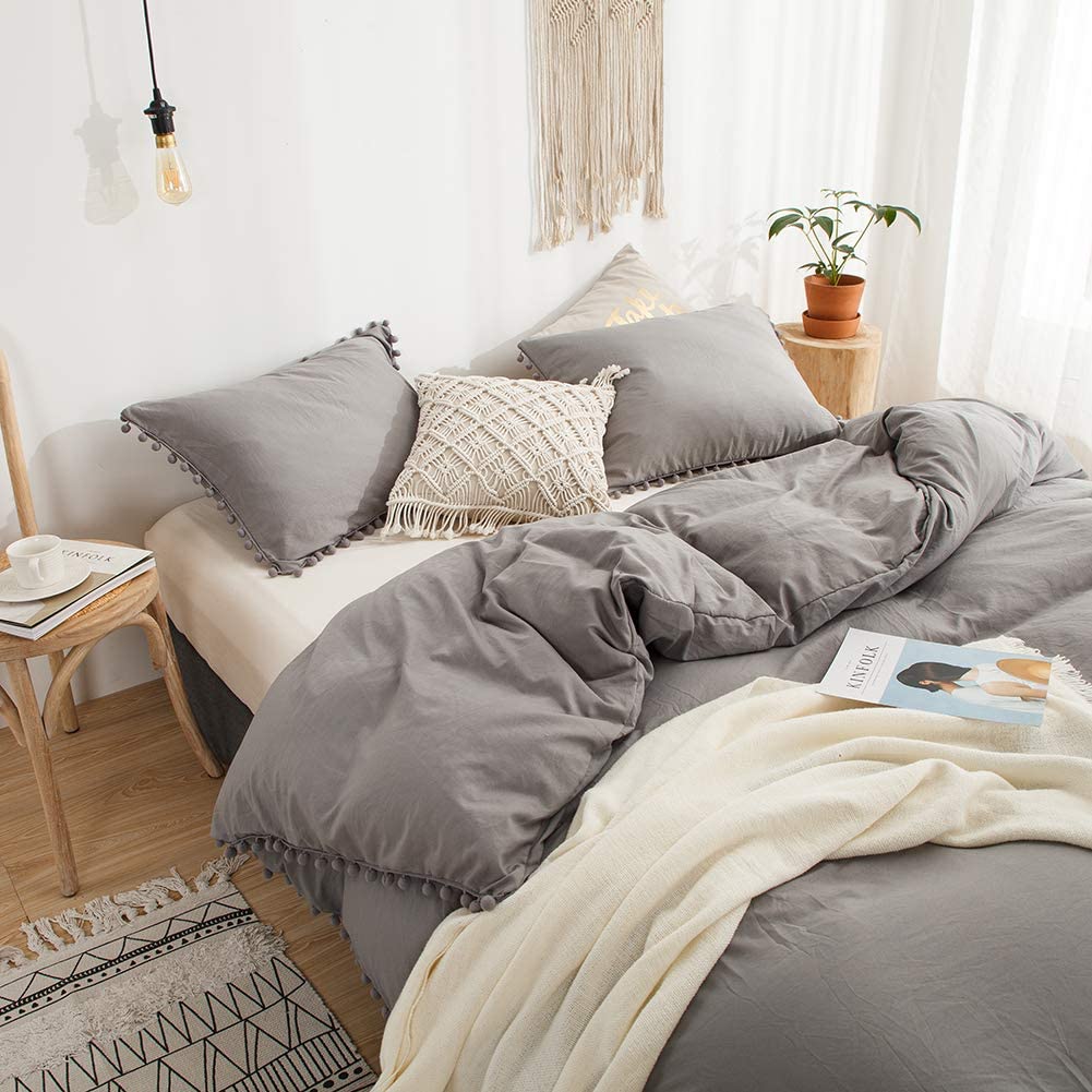 Aerial side view of the VibeCore Aesthetic PomPom Duvet Cover Set in light gray, featuring playful pom-pom accents along the edges. Crafted from soft, breathable fabric, this duvet set brings a cozy, whimsical touch and modern vibe to any bedroom or dorm.