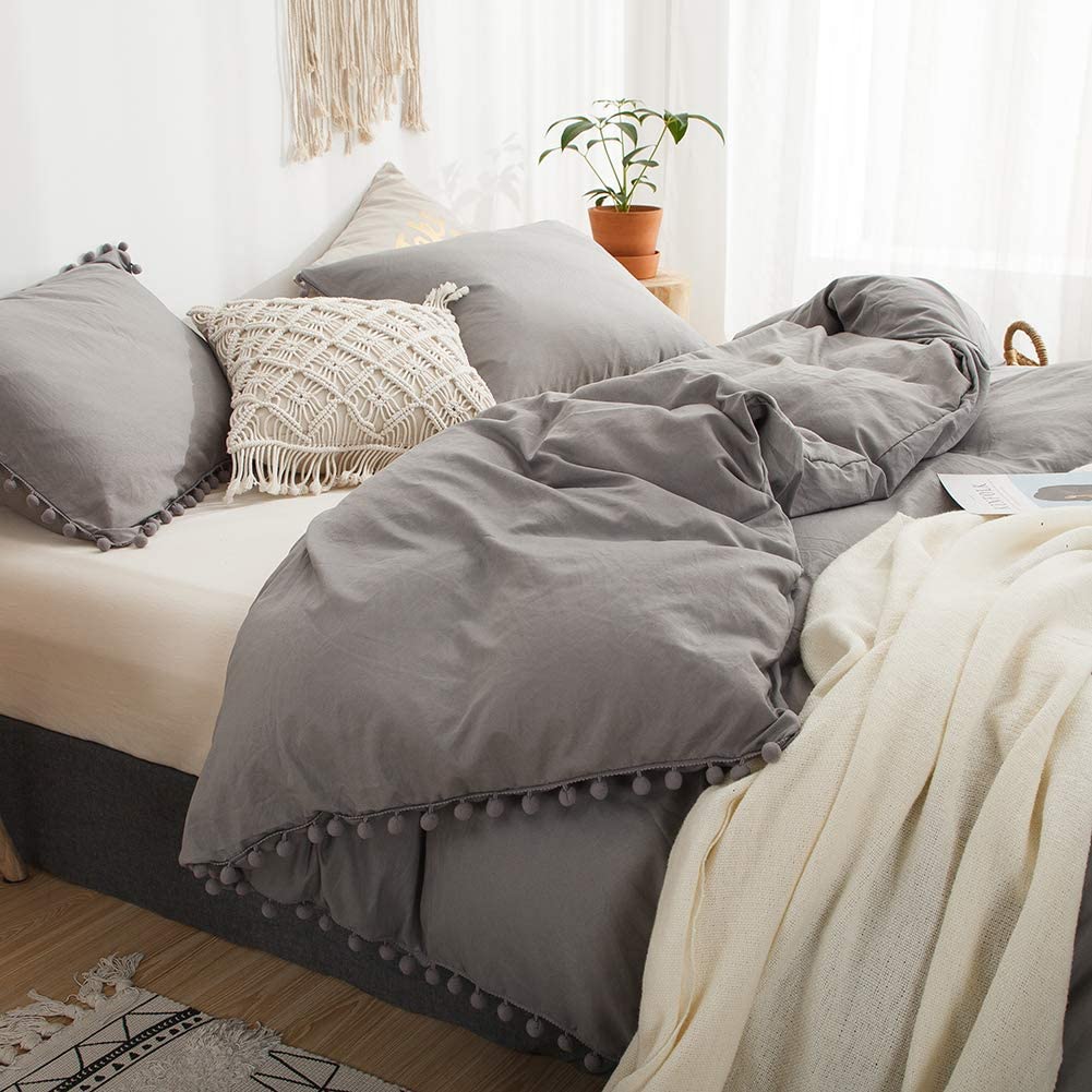 Side view of the VibeCore Aesthetic PomPom Duvet Cover Set in light gray, highlighting the playful pom-pom accents along the edges. Made from soft, breathable fabric, this duvet set adds a cozy, whimsical touch to any bedroom or dorm.