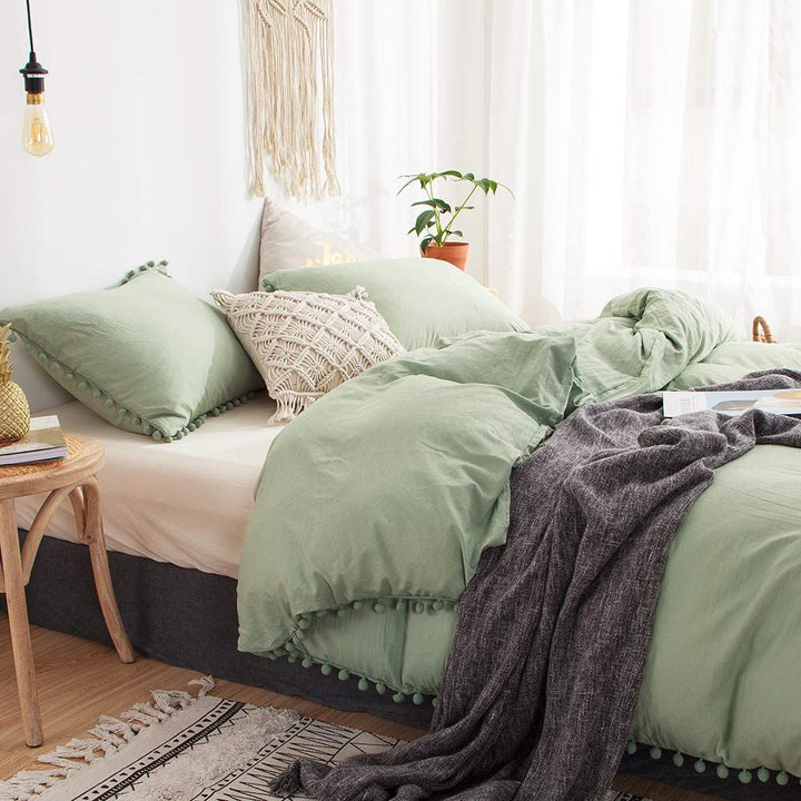 Side view of the VibeCore Aesthetic PomPom Duvet Cover Set in pastel green, highlighting the playful pom-pom accents along the edges. Made from soft, breathable fabric, this duvet set adds a cozy, whimsical touch to any bedroom or dorm.