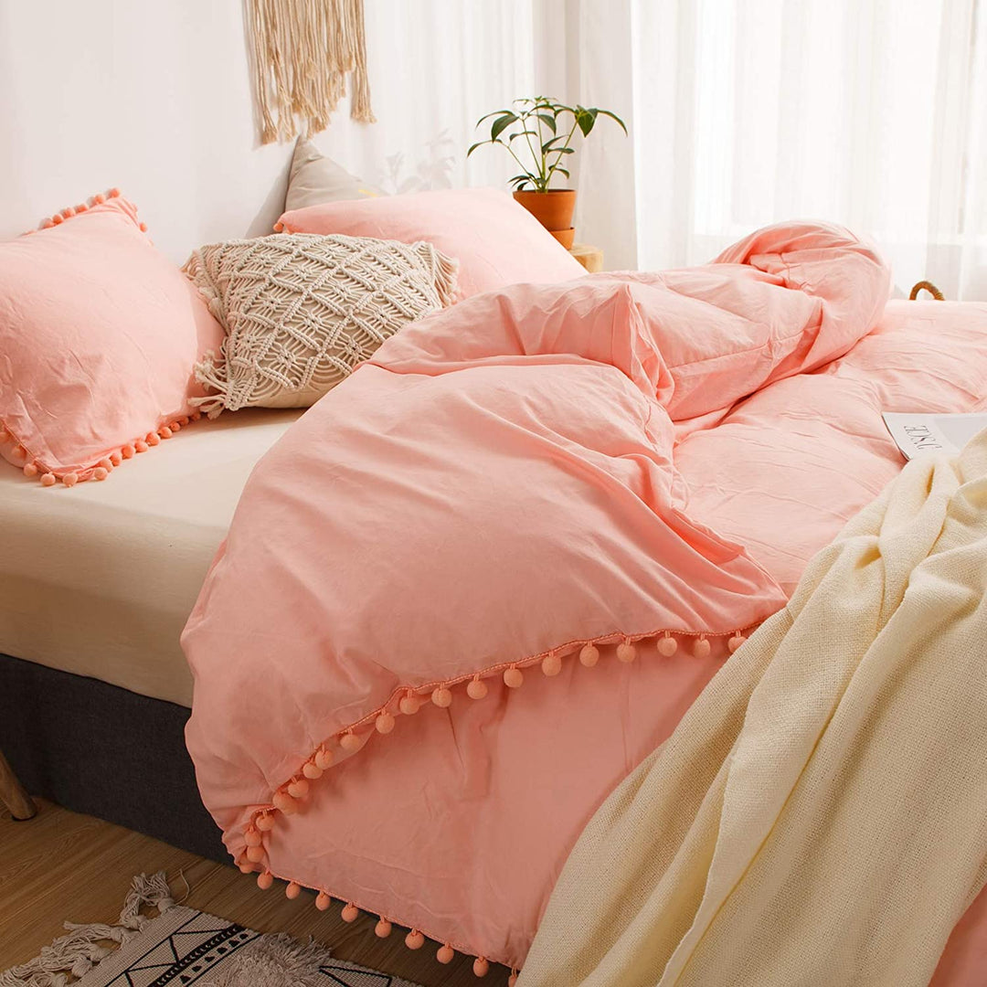 Close-up side view of the VibeCore Aesthetic PomPom Duvet Cover Set in rose, highlighting the soft, playful pom-pom detailing along the edges. Made from soft, breathable fabric, this duvet set adds a cozy, whimsical touch to any bedroom or dorm with its warm, inviting tone.