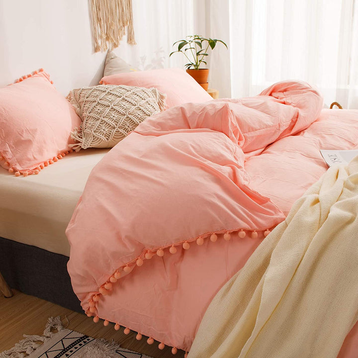 Close-up side view of the VibeCore Aesthetic PomPom Duvet Cover Set in rose, highlighting the soft, playful pom-pom detailing along the edges. Made from soft, breathable fabric, this duvet set adds a cozy, whimsical touch to any bedroom or dorm with its warm, inviting tone.