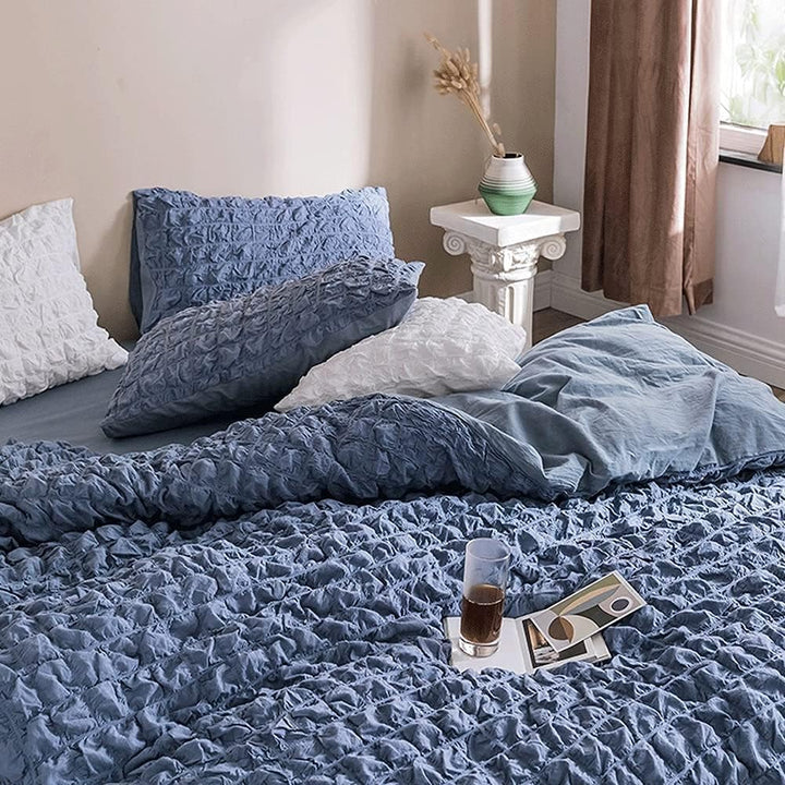 Experience effortless elegance with the VibeCore Aesthetic Tufted Duvet Cover Set in blue. From the angled aerial view, the intricate tufted design and soft, plush texture bring a sense of comfort and style to your space. The gentle rose hue adds a touch of warmth and sophistication, making this duvet cover set the perfect centerpiece for a chic, cozy bedroom.
