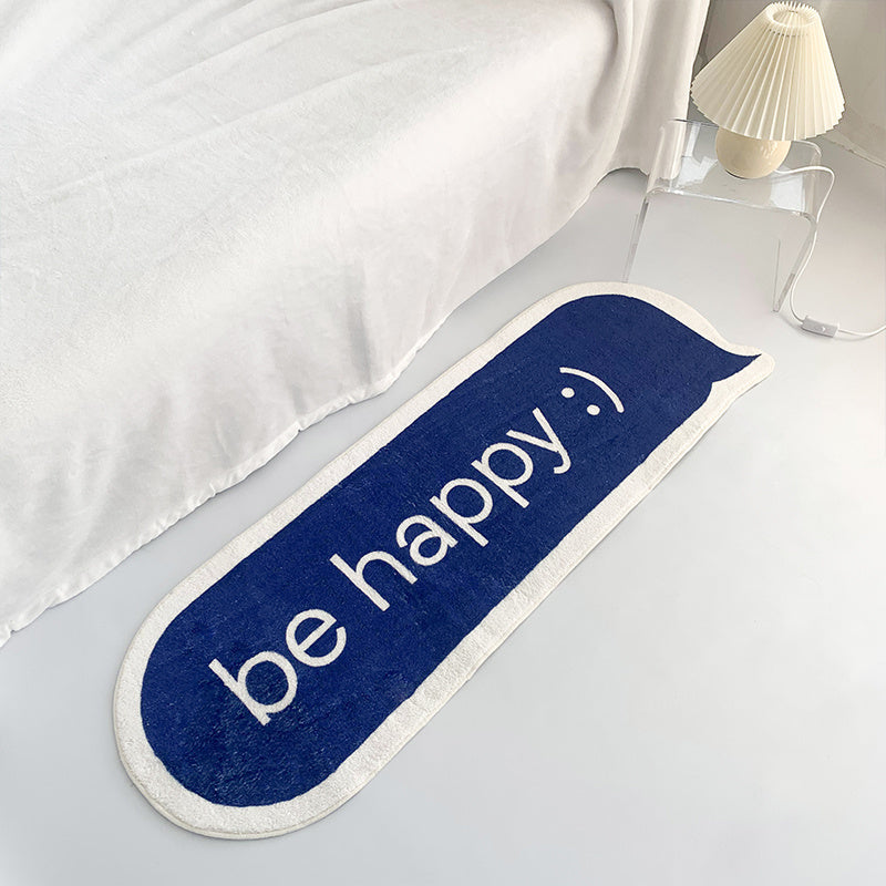 VibeCore Be Happy iMessage Accent Rug seen from an aerial view at the foot of a bed. The vibrant blue rug adds a playful touch, perfectly complementing the room's cozy vibe. The plush texture and non-slip backing are visible, enhancing the room's charm and ensuring safety.