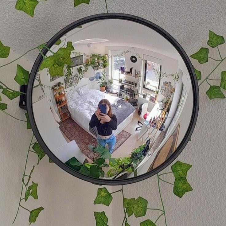 VibeCore Black Convex Traffic Mirror in room, with girl taking a selfie. Featuring a bold black frame and wide-angle lens, this grunge-style convex mirror offers a unique fish-eye effect, enhancing visibility and adding a retro, urban vibe. Perfect for selfies and modern decor, it combines both style and function, making a bold statement with its sleek, industrial flair.