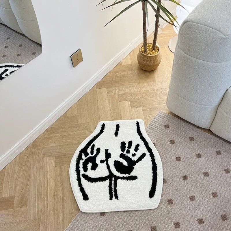 The VibeCore Booty Handprints Accent Rug placed in a living room, showcasing its bold black-and-white handprint design. This quirky and unique rug adds personality and a playful vibe to modern or minimal interiors. Its soft, plush texture enhances comfort, making it a standout piece for living room decor while bringing a touch of humor and style.
