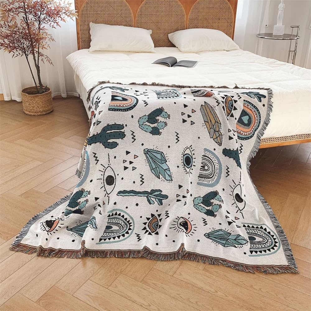 VibeCore Cactus & Crystals Woven Blanket draped over the corner of a bed, showcasing its boho-inspired cactus and crystal design with soft, breathable cotton texture.