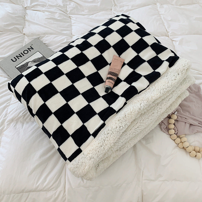 Black and white checkerboard fleece throw blanket folded on a bed, showcasing its bold design and ultra-soft milk velvet texture. Stylish, cozy, and perfect for any space.