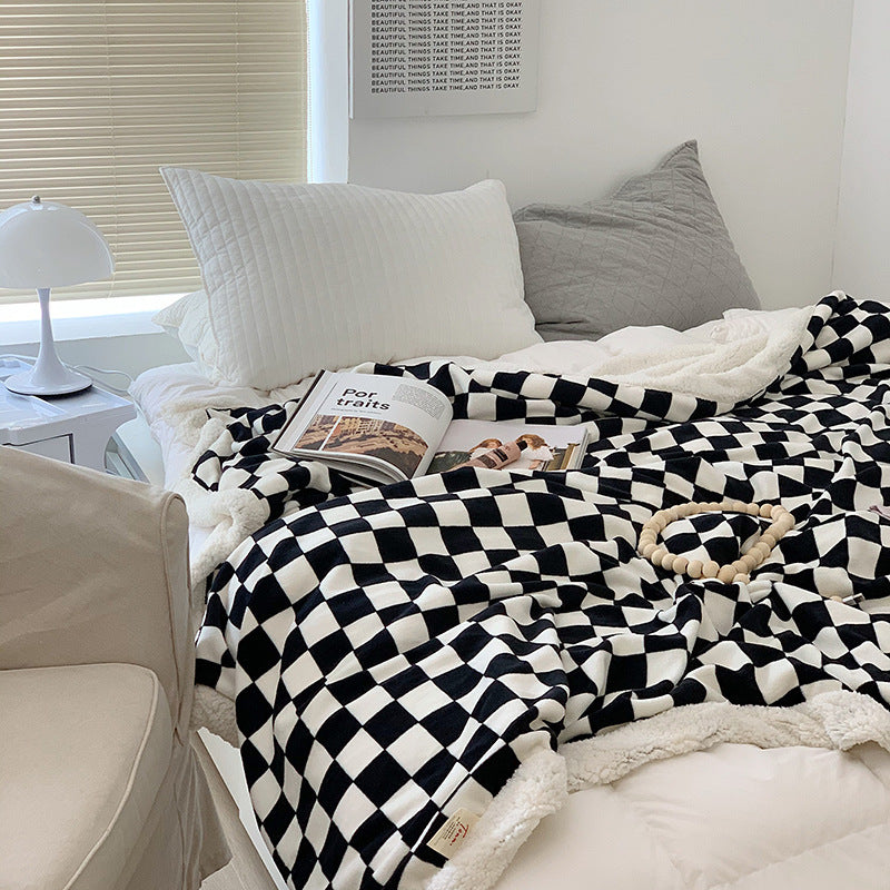 Black and white checkerboard fleece throw blanket on a bed, adding a bold, modern touch. Ultra-soft milk velvet material for cozy comfort. Perfect for dorms, bedrooms, and lounging.