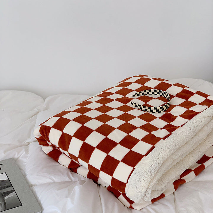 Red and white checkerboard fleece throw blanket folded on a bed, showcasing its plush milk velvet texture and bold, modern design. Cozy and stylish for any space.