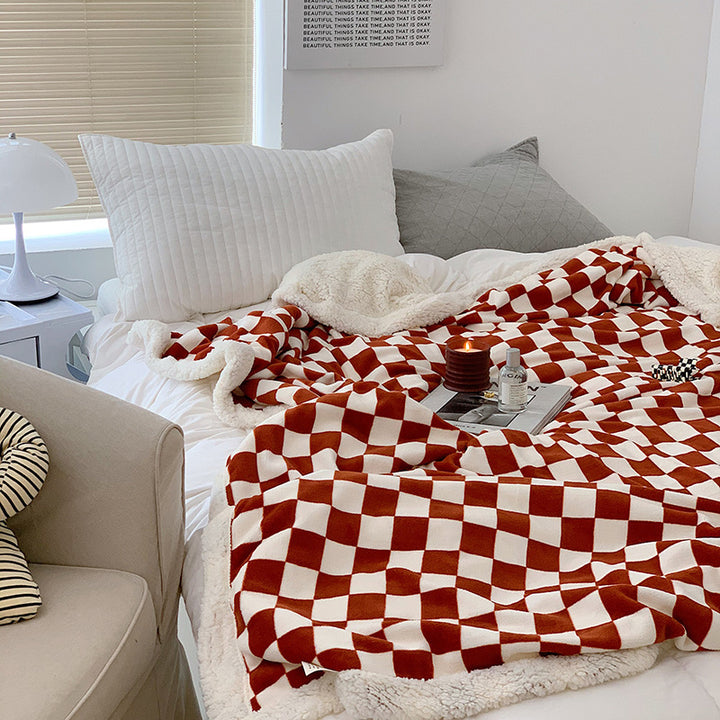 Red and white checkerboard fleece throw blanket on a bed, featuring a bold design and ultra-soft milk velvet texture. Cozy, stylish, and perfect for any space.