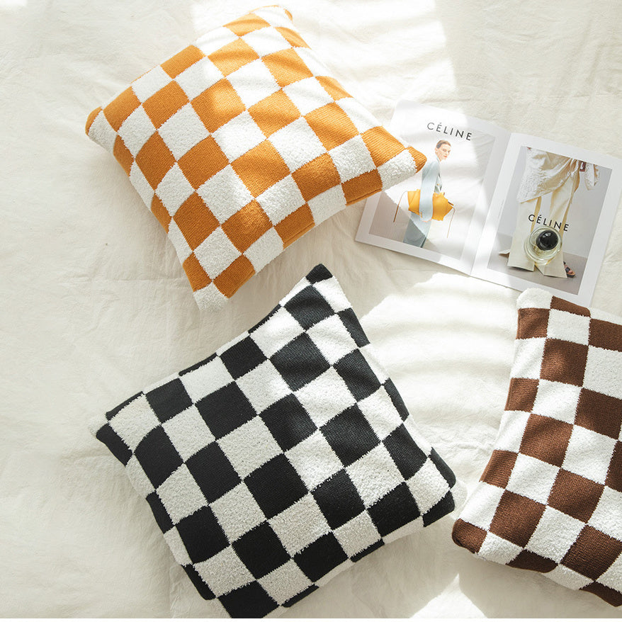 Top view of VibeCore Checkerboard Throw Pillow Covers in orange and black, featuring bold checkerboard patterns. Soft polyester-cotton blend for a stylish and modern touch to any room or couch.