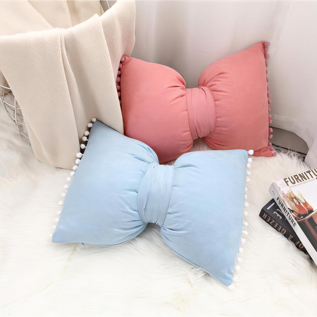 VibeCore Classic Bow Throw Pillow in pink and sky blue, showcasing its playful bow shape and pom-pom accents, adding a chic and cozy touch to a stylish room decor.