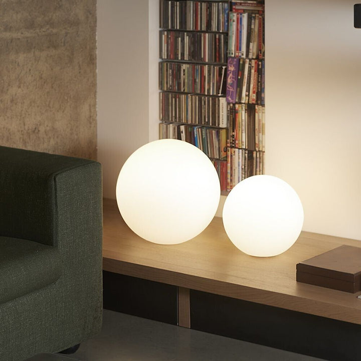 Two sizes of the VibeCore Color-Changing LED Glow Ball in a living room setting, displaying their vibrant colors and glowing ambiance.