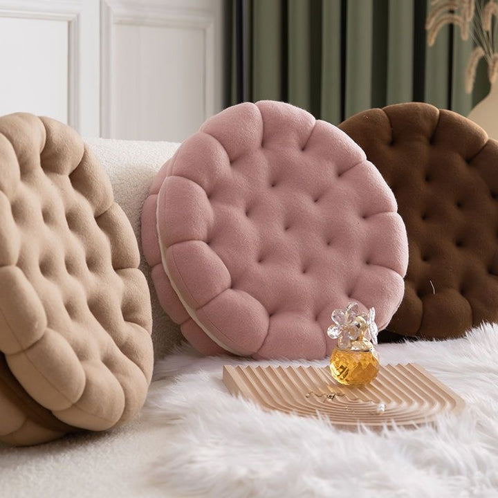 VibeCore Cookie Sandwich Throw Pillow in three colors (almond, chocolate, and strawberry) arranged against a cozy couch, showcasing its playful design and plush texture.
