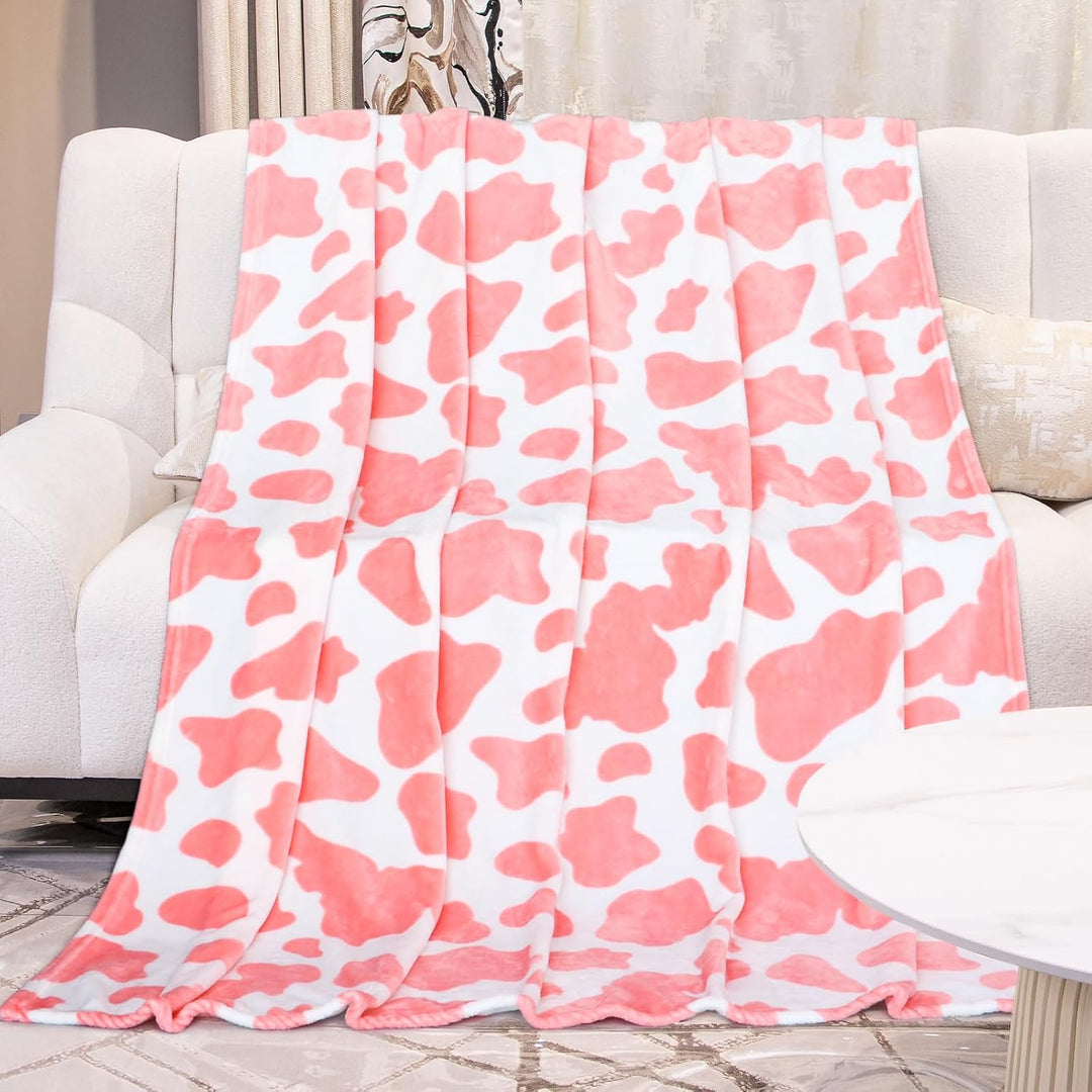 Light pink cow print throw blanket draped straight on a sofa, adding a playful and trendy touch to your space. Soft and cozy, perfect for enhancing your living room with style and comfort.