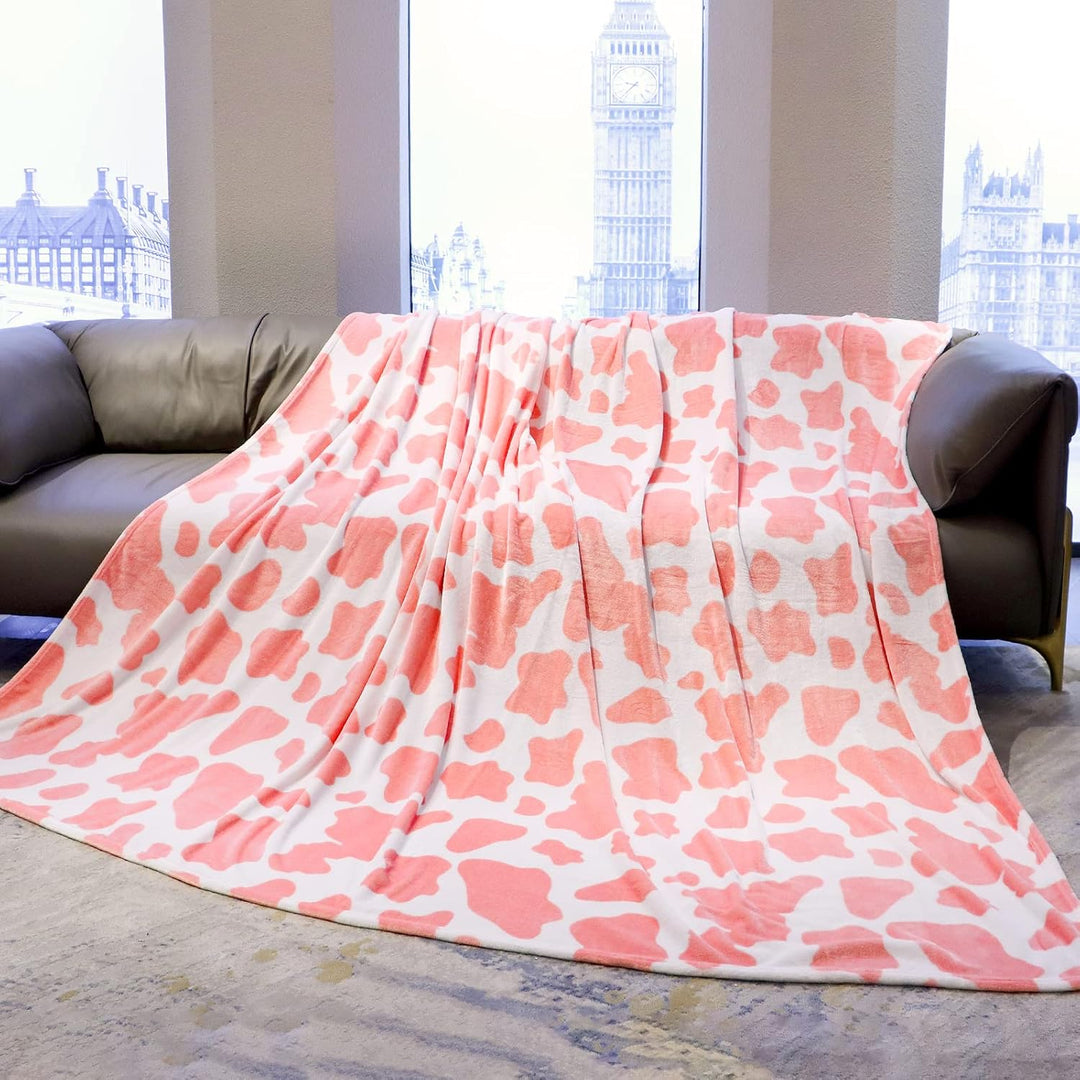 Light pink and white cow print throw blanket draped over a sofa, adding a bold, trendy touch to your space. Soft, cozy, and perfect for enhancing your living room with personality and style.