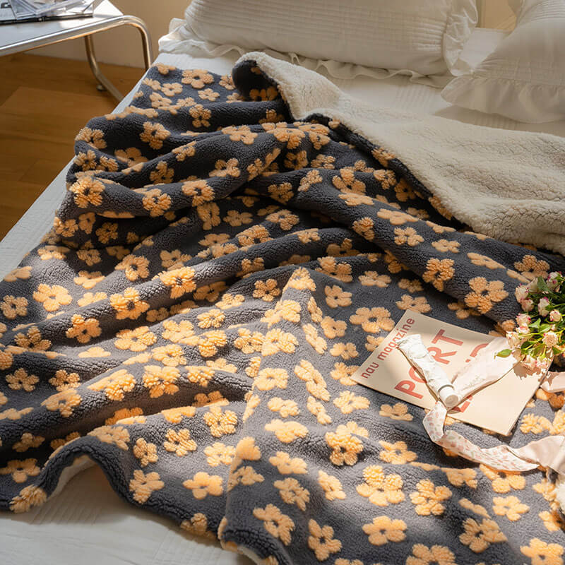 Aerial view of a navy Delicate Florals Fleece Throw Blanket on a bed, showcasing its bold 70s-inspired floral design and ultra-soft coral fleece texture. A cozy, retro touch to enhance your bedroom decor.