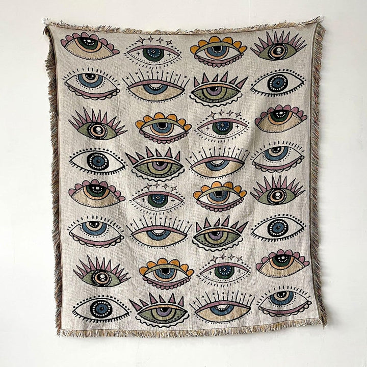 VibeCore Eternal Gaze Woven Blanket product view, showcasing its captivating and bold design. Crafted from soft, breathable 100% combed cotton, this versatile blanket features reversible patterns for effortless style changes, adding depth and mystique to any room.