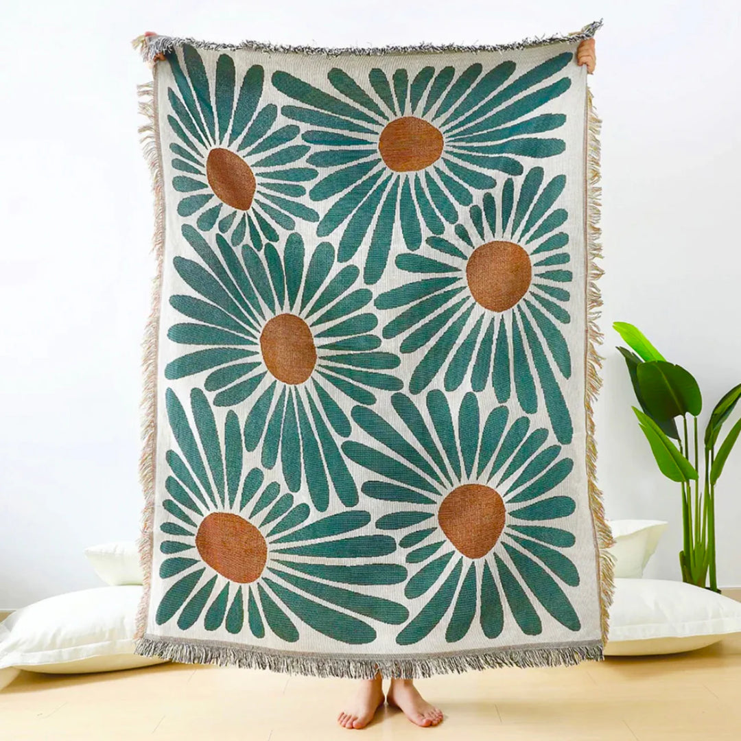 VibeCore Floral Fusion Woven Blanket being held up, showcasing its intricate floral design. Crafted from soft, breathable 100% combed cotton, it adds charm and artistic beauty to any space, offering versatile styling as a throw, wall hanging, rug, or tablecloth with its reversible patterns.