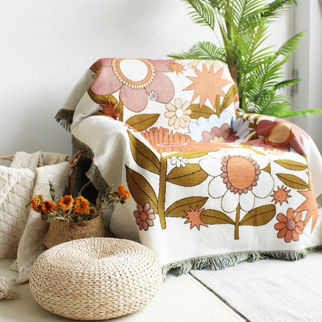 VibeCore Flower Power Woven Blanket draped over chair, showcasing its eye-catching floral design, reversible patterns, and soft, breathable 100% combed cotton. Adds vibrant, cozy style and versatility to any space.