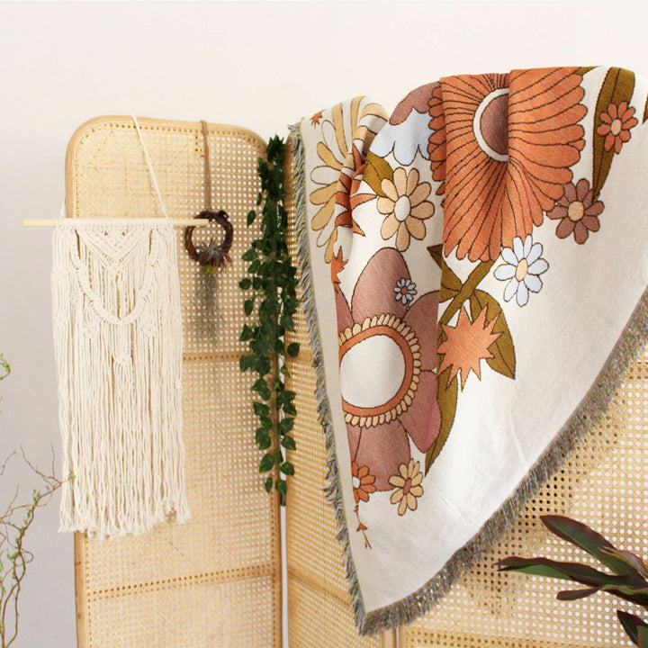 VibeCore Flower Power Woven Blanket on room divider, featuring a bold floral design and reversible patterns. Made from soft, breathable 100% combed cotton, it adds vibrant, cozy style and a unique touch to your space.