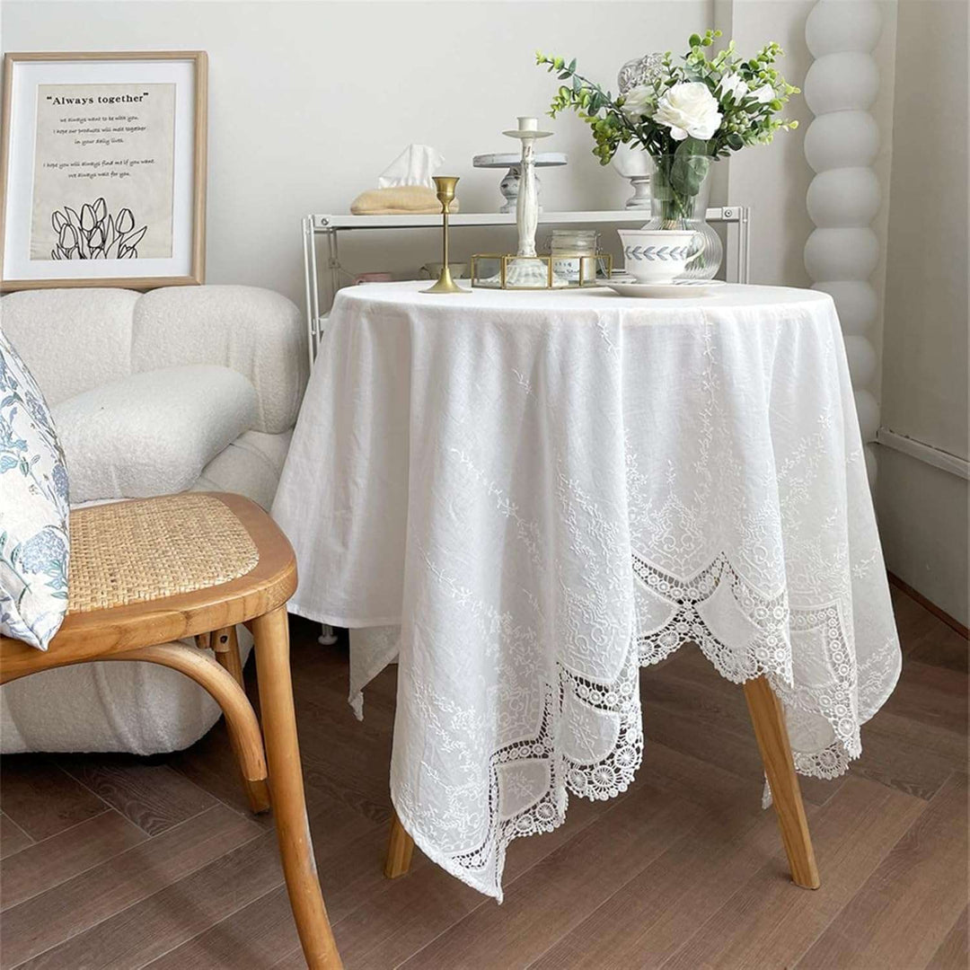 VibeCore French White Lace Tablecloth on small table, delicate Anemone lace, vintage-inspired decor, soft cotton material, elegant dining or accent piece.