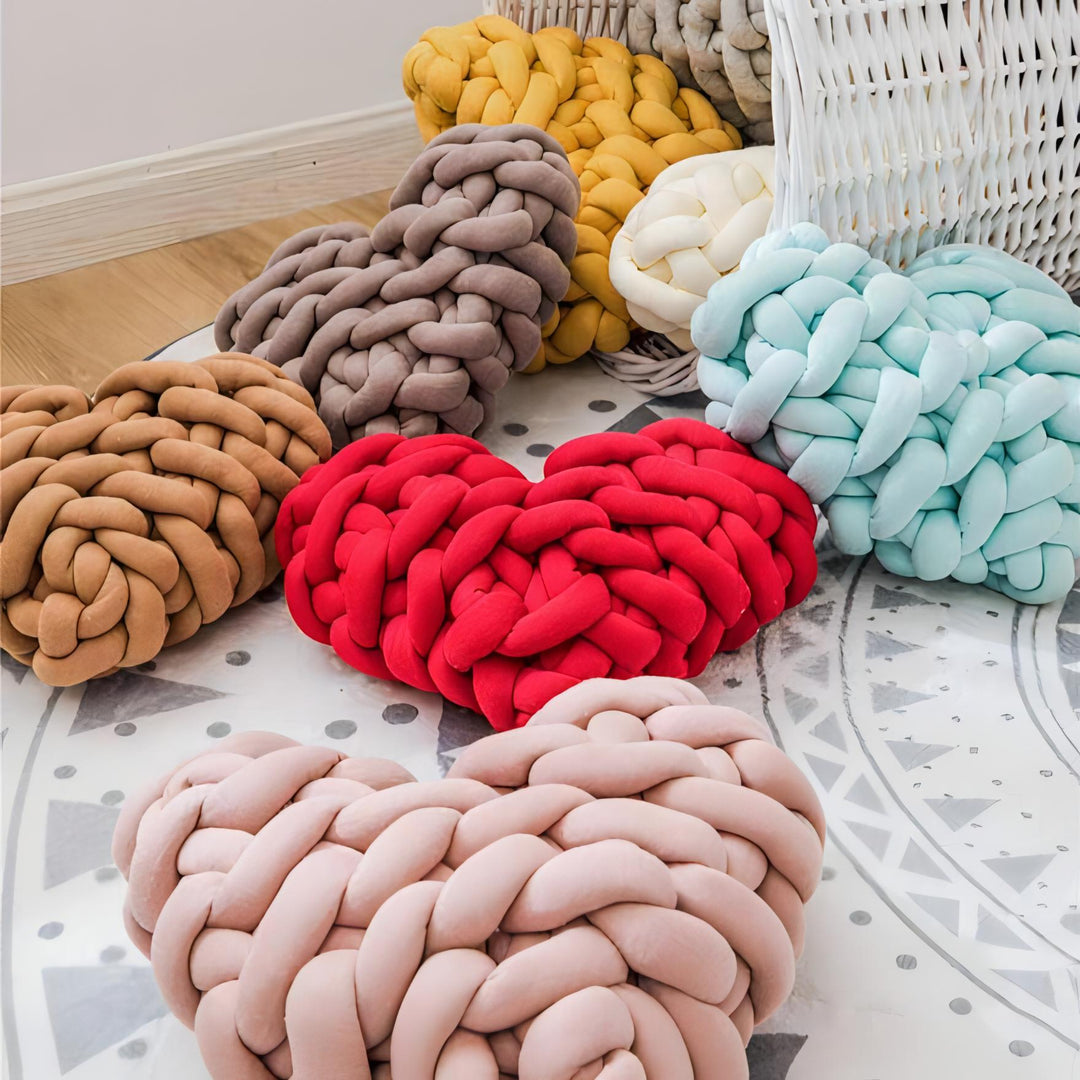 VibeCore Heart-Shaped Knot Throw Pillow in all colors, close-up view, showcasing its heart-shaped, woven knot design. Crafted from soft polyester fiber, this plush pillow adds a unique, cozy accent to your space, combining comfort with a charming, stylish texture.