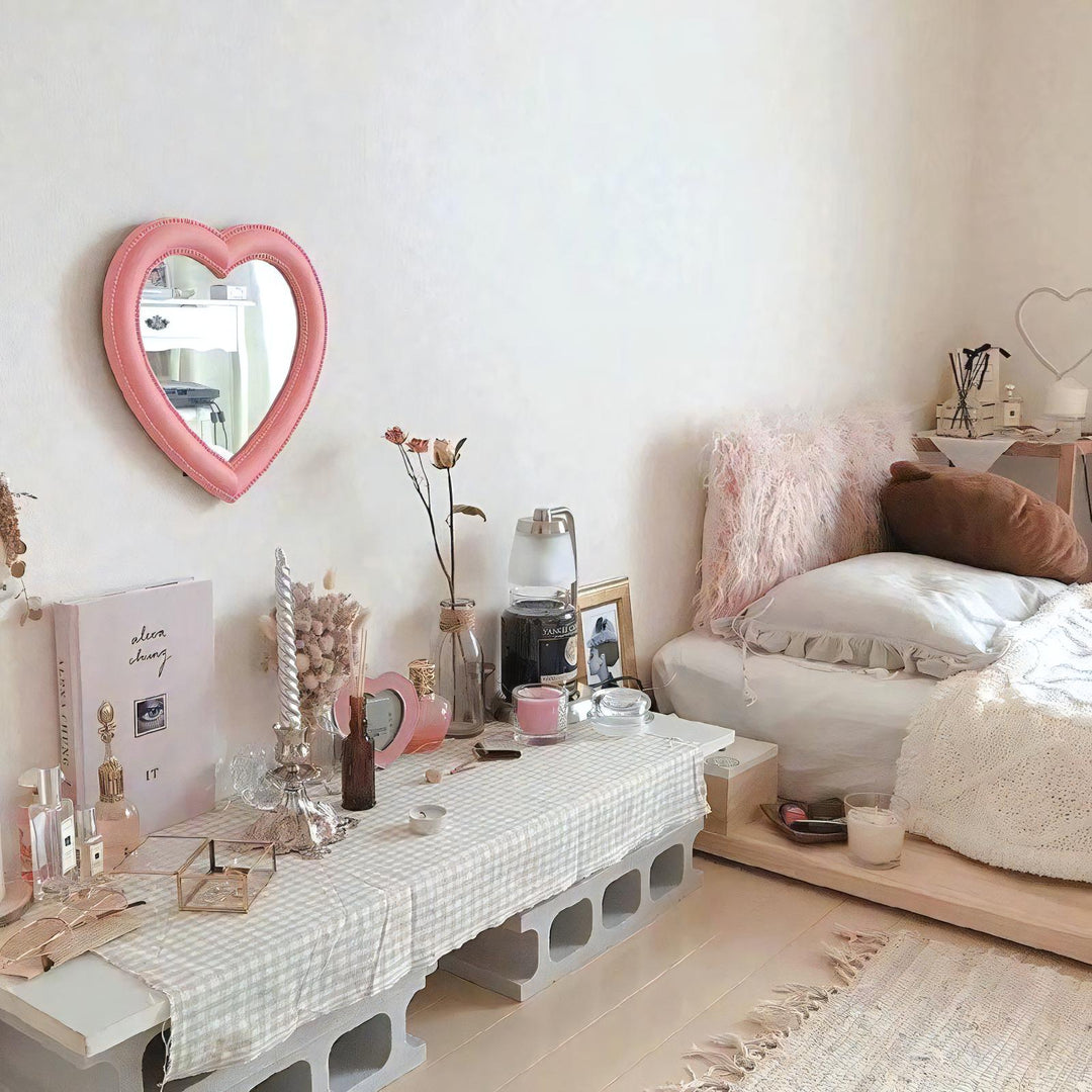 VibeCore Heart-Shaped Mirror in Pink, hanging on a bedroom wall, creating a cozy, aesthetic vibe. Perfect for a cutecore or coquette-inspired room, this mirror adds a trendy touch to any teen room or dorm room. Its soft pink hue enhances the modern, feminine decor while reflecting a stylish and playful aesthetic, ideal for anyone looking to elevate their space with cute and functional decor.