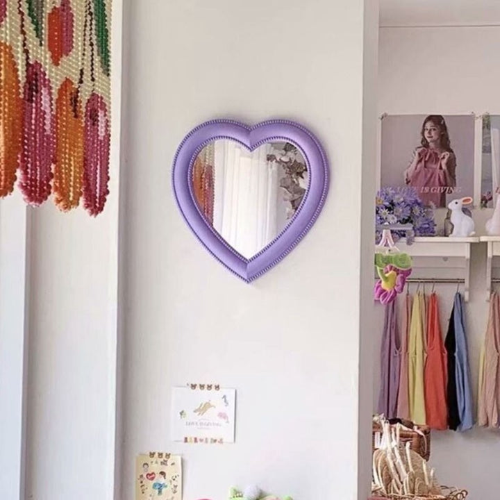 VibeCore Heart-Shaped Mirror in Purple, hanging on the wall, perfect for adding a coquette or cutecore touch to any room. This aesthetic mirror enhances teen rooms, dorm rooms, or bedrooms, creating a vibrant and charming space. Its soft purple tone brings a whimsical and playful vibe, making it a must-have for those looking to elevate their decor with a cute, trendy aesthetic.