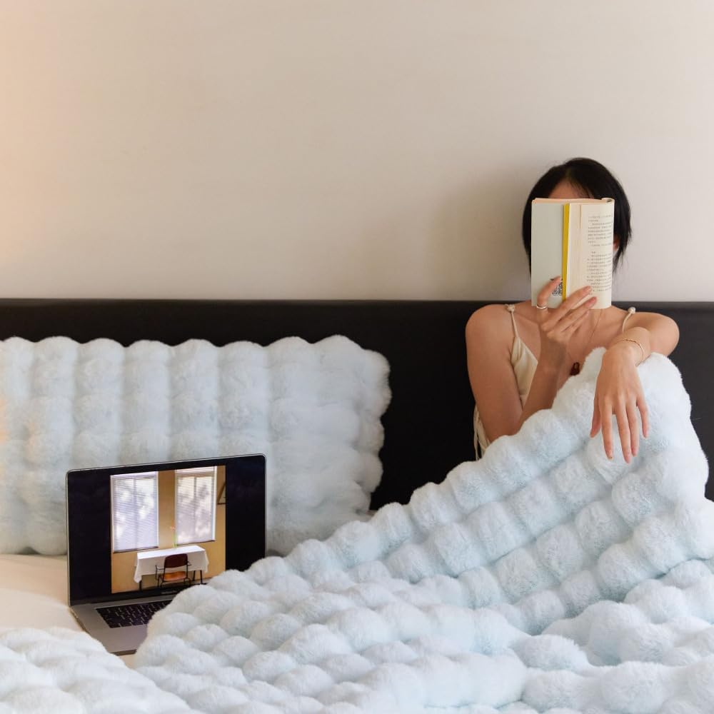 VibeCore Marshmallow Ultra Plush Blanket Pastel Blue With Woman Cuddled Up In Bed, demonstrating how cozy the blanket is.