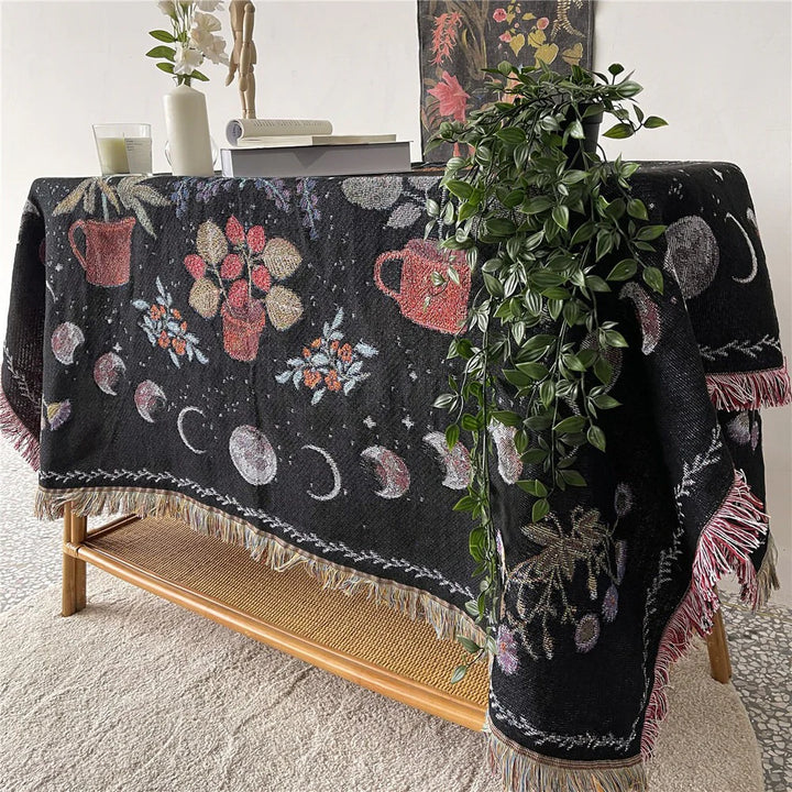 VibeCore Mystic Bloom Woven Blanket draped over a table, displaying its vibrant floral design, made from soft 100% combed cotton, ideal for adding an enchanting touch to your decor.