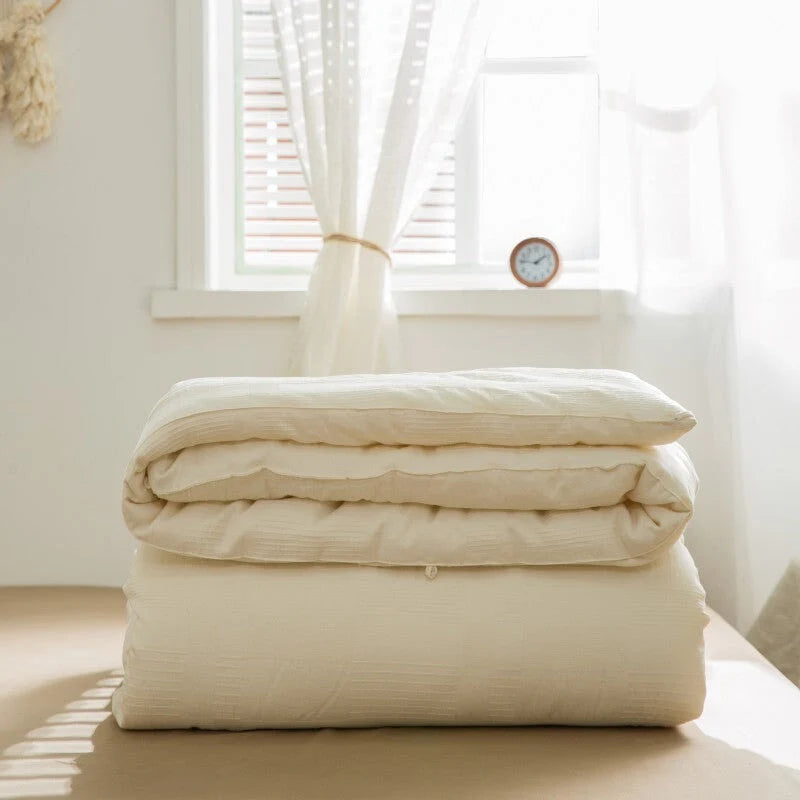 Folded VibeCore Organic Soybean Fiber Duvet Insert on a bed with a window in the background