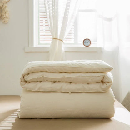 Folded VibeCore Organic Soybean Fiber Duvet Insert on a bed with a window in the background