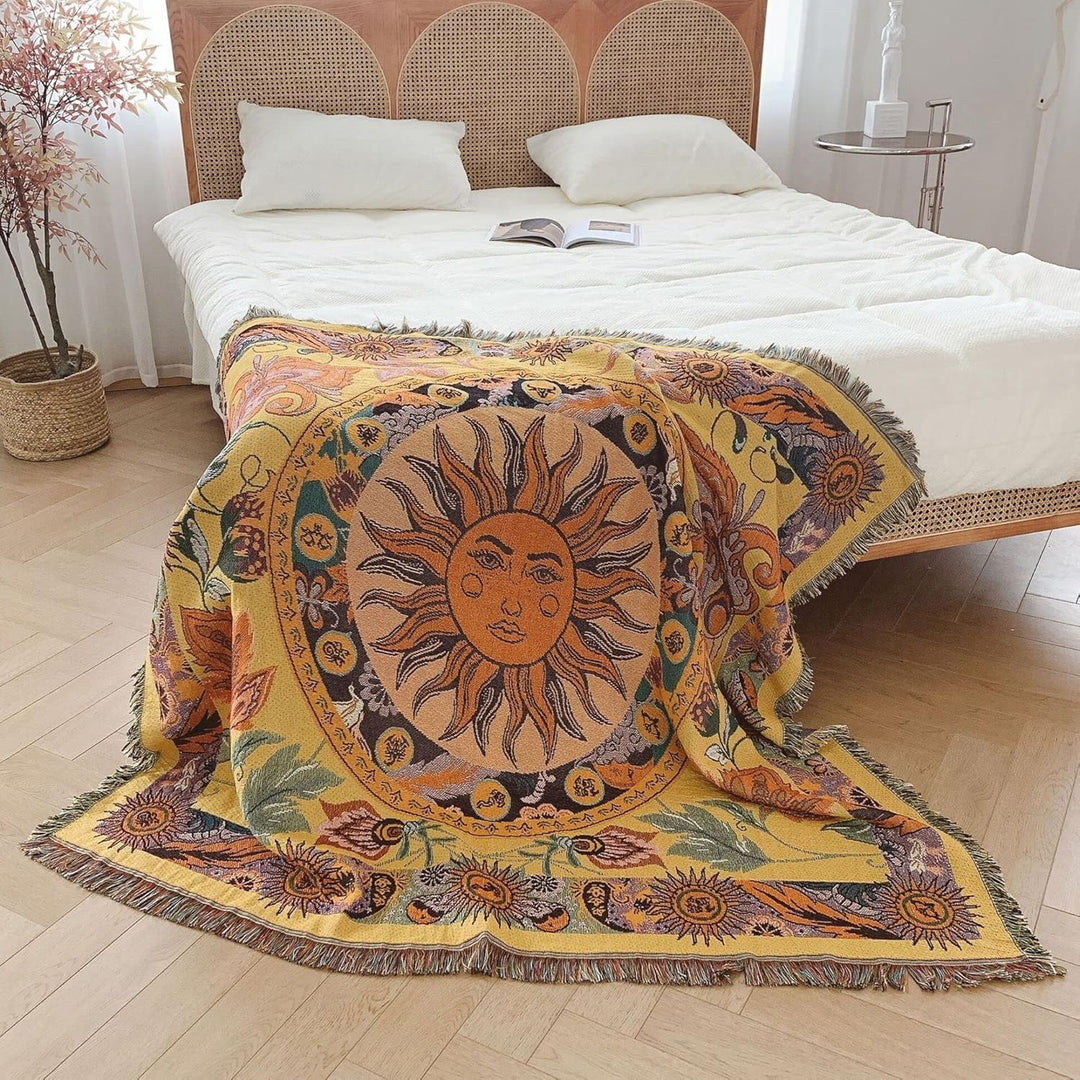 VibeCore Radiant Sun Woven Blanket draped over the corner of bed, showcasing vibrant boho-sun design and soft 100% combed cotton fabric.