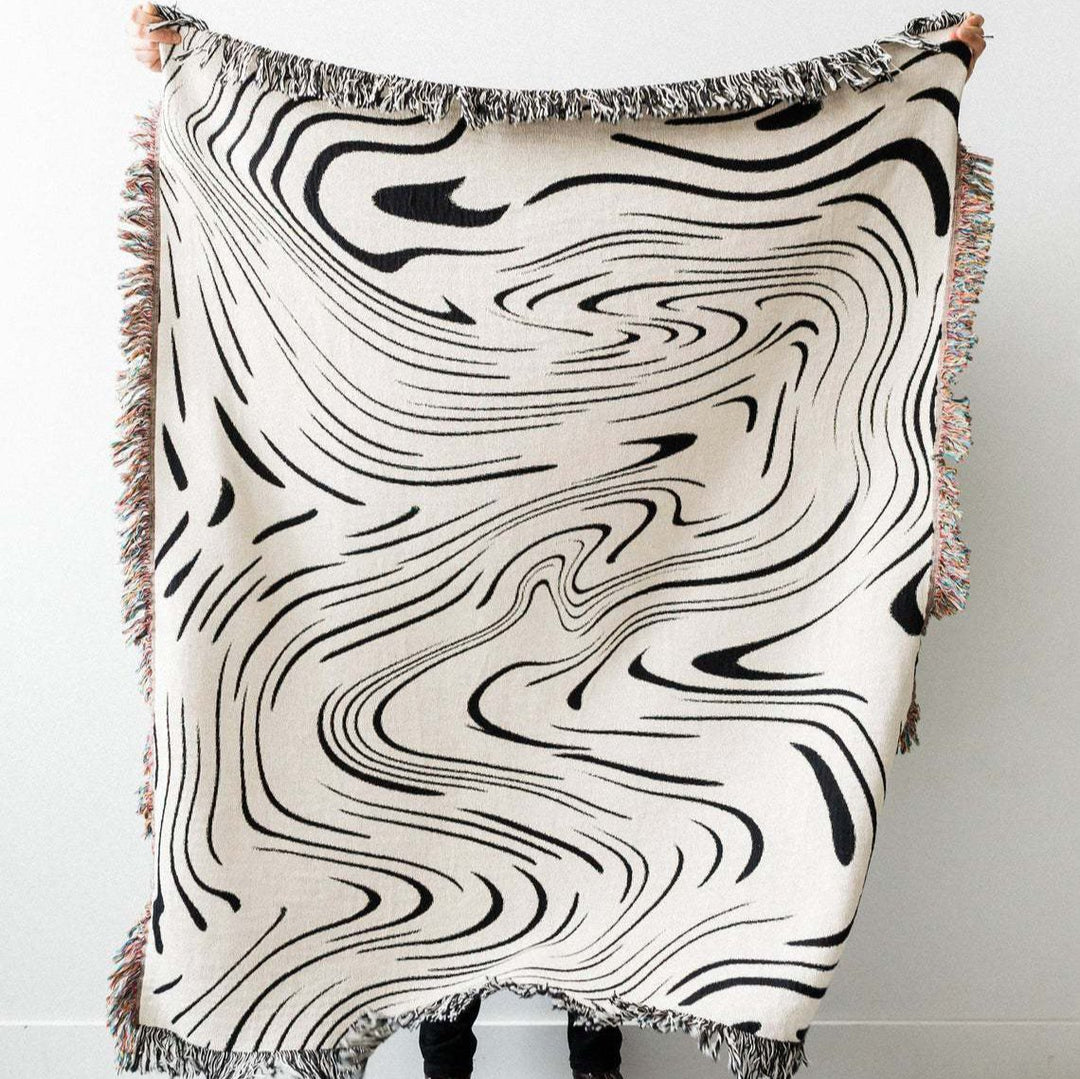 VibeCore Retro Marble Wave Woven Blanket being held up, showcasing spiritual-inspired cosmic design and vibrant reversible patterns in soft 100% combed cotton.