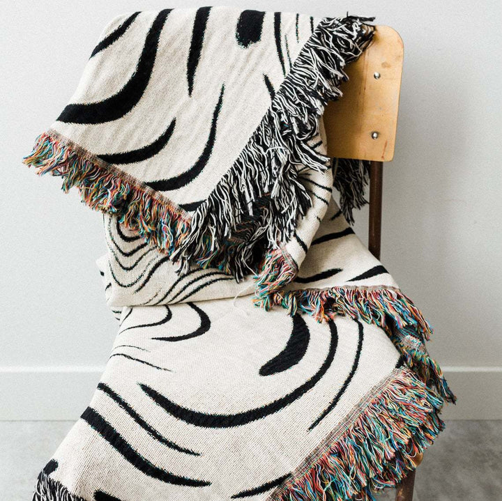 VibeCore Retro Marble Wave Woven Blanket folded over chair, top view showcasing spiritual-inspired cosmic design and soft 100% combed cotton texture.