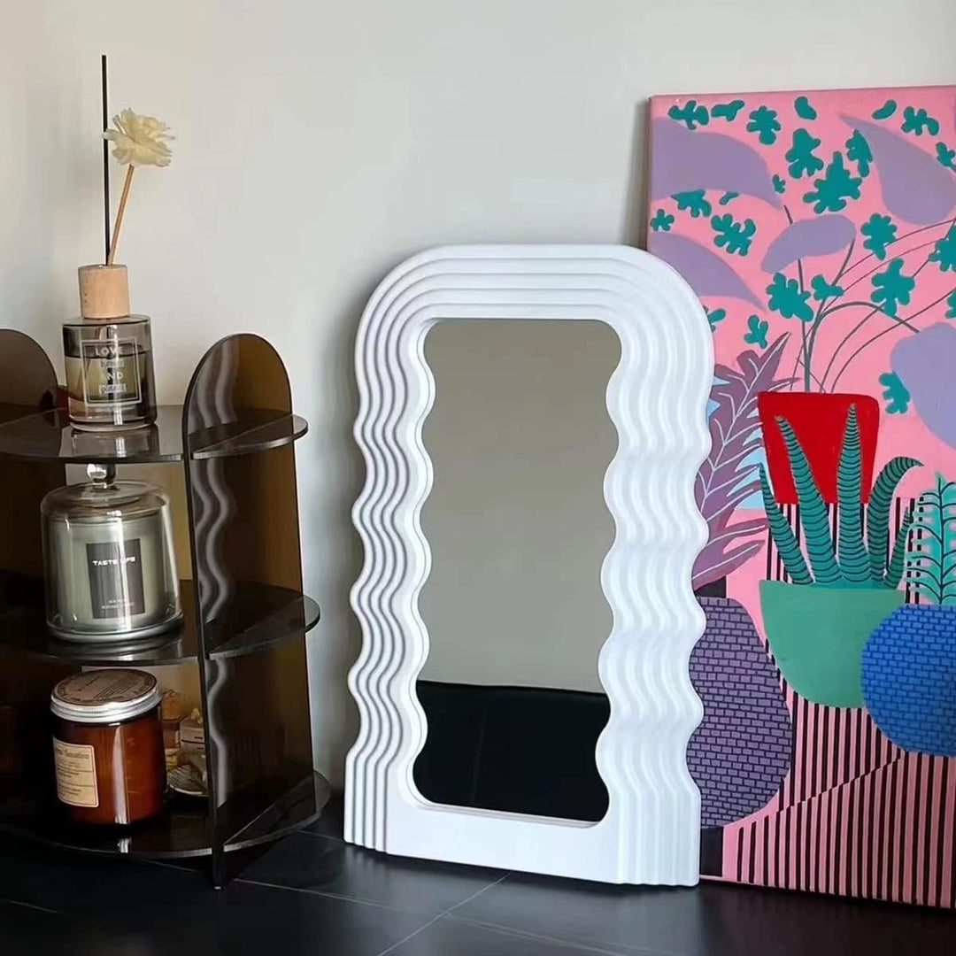 VibeCore Retro Wave Mirror in white, leaning against a wall, featuring a wave-shaped resin frame and sleek mirror lens, creating a stylish and modern focal point in the room.