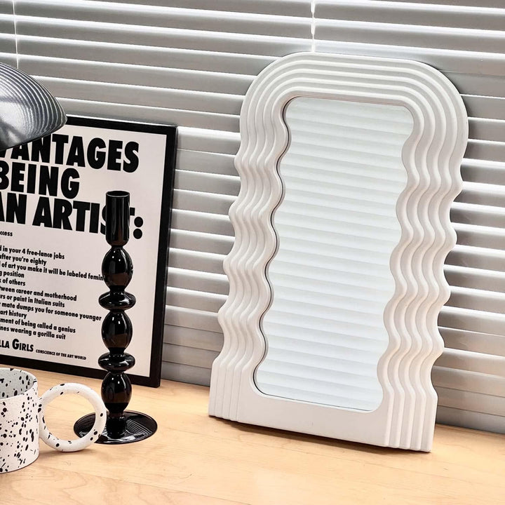 VibeCore Retro Wave Mirror in white, leaning against a window, showcasing its wave-shaped resin frame and sleek mirror lens, adding a modern and artistic touch to the space.