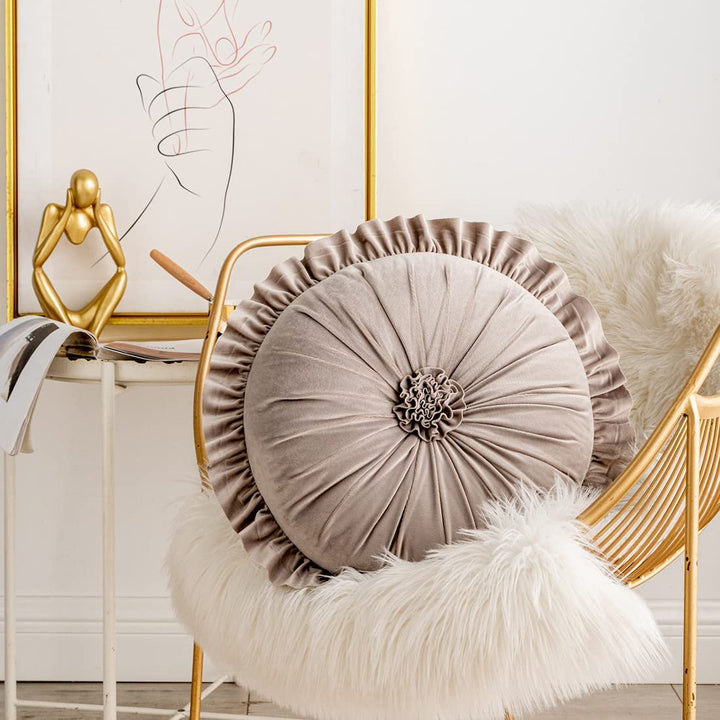 VibeCore Round Tufted Flower Throw Pillow in beige, featuring a ruffled flower design and luxurious Dutch velvet, styled on a chair for an elegant and cozy room accent.