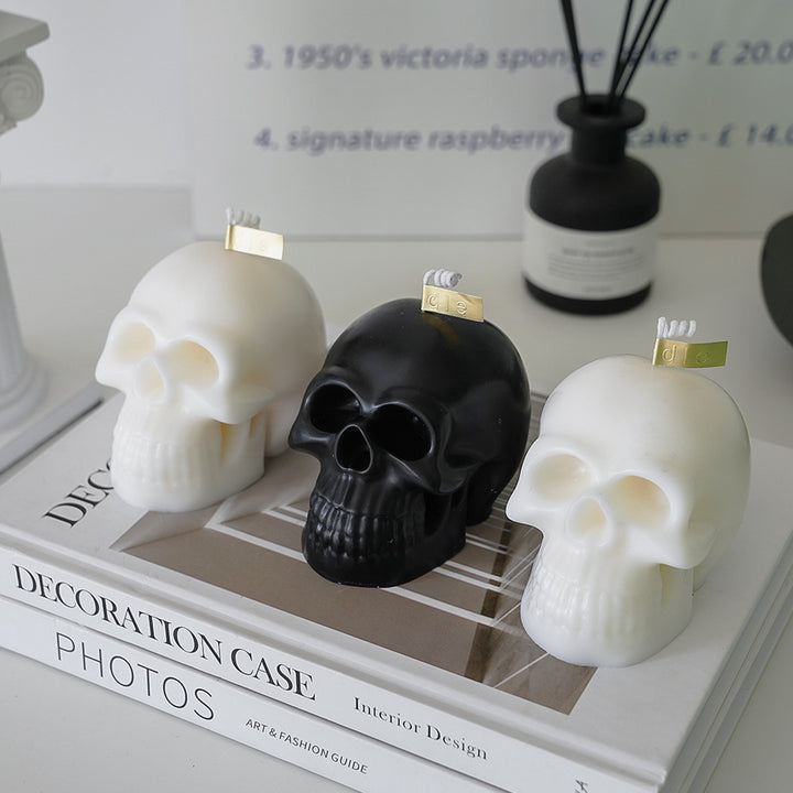 Two white scented skull candles and one black scented skull candle, featuring bold, striking designs and captivating fragrances, perfect for adding an edgy touch to your room decor.