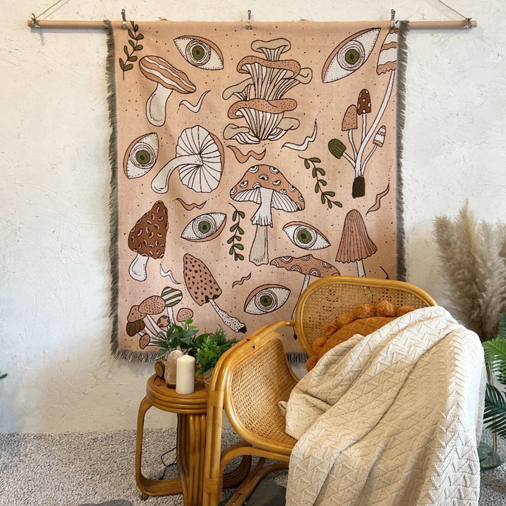 VibeCore Shroom Magic Woven Blanket displayed as a wall hanging, highlighting its enchanting mushroom design and reversible woven texture.