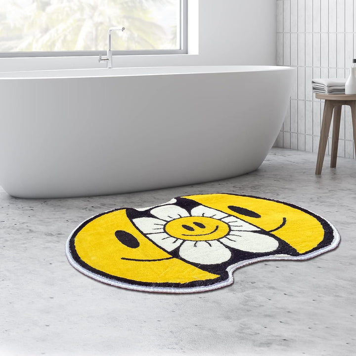 VibeCore Sunshine Split Smiley Accent Rug in front of a bathtub, featuring a playful design with a smiling face splitting open to reveal a vibrant sunflower, adding charm to the bathroom decor.